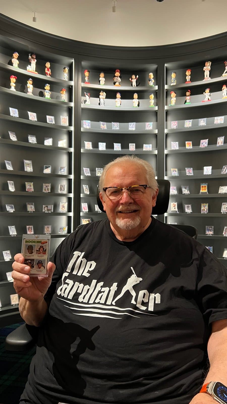 The CardFather in a Cardfather tee, holding up a card in front of his collection.