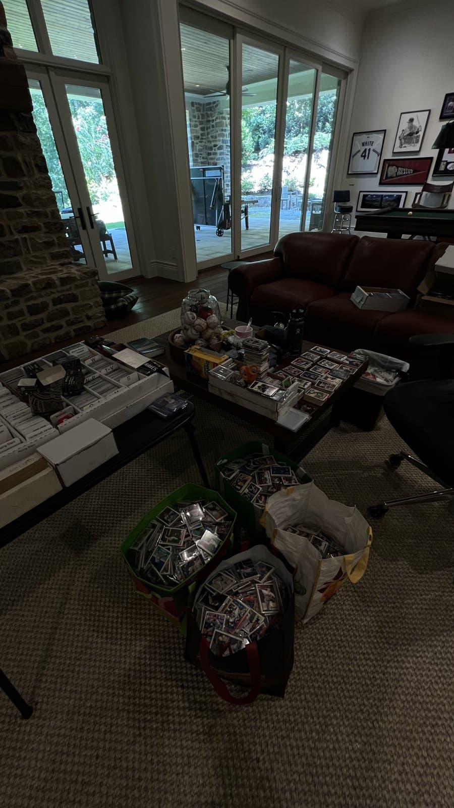 Bags of sorted cards on the floor and boxes spread across a table, mid-knit.