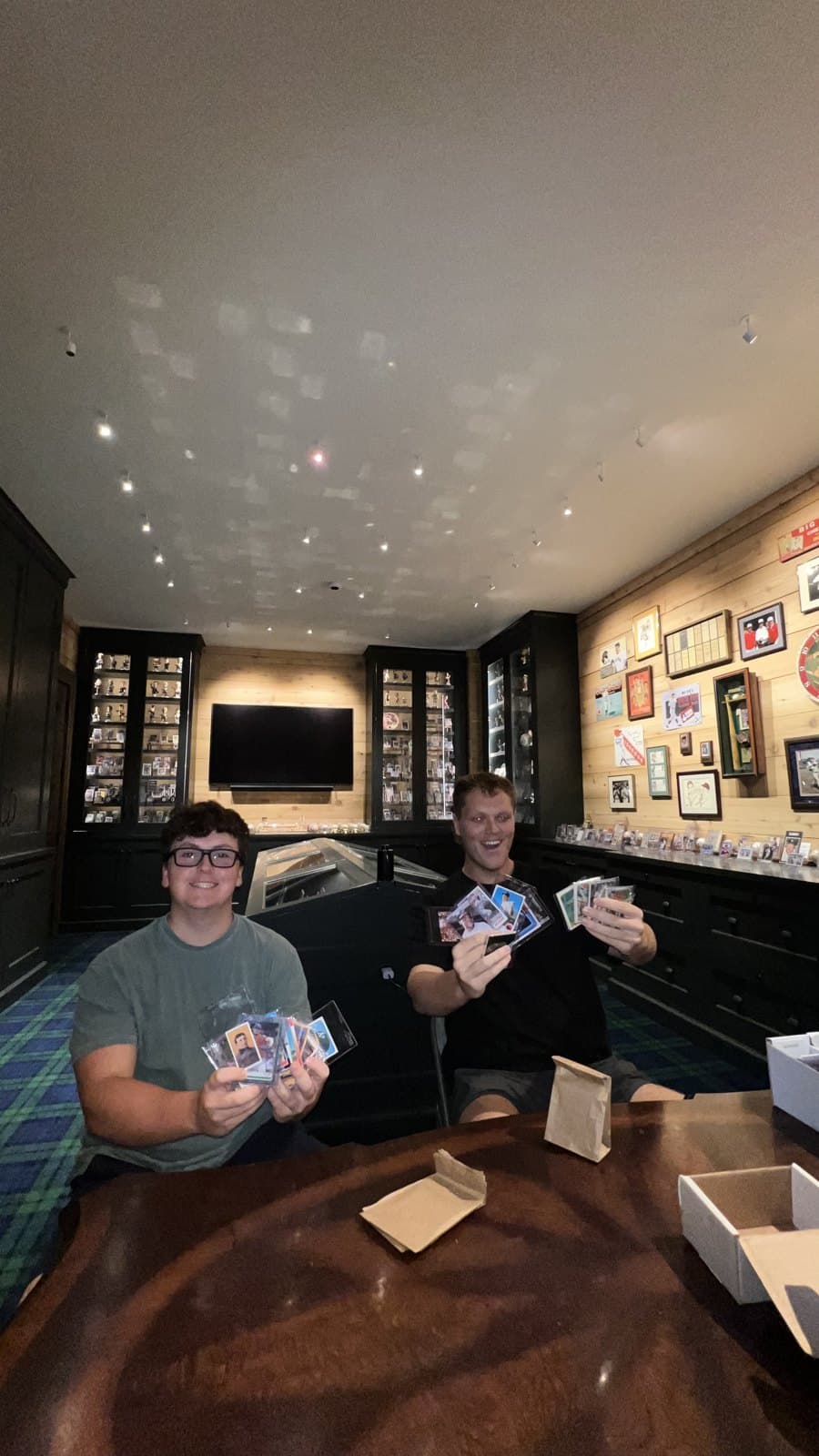 Two visitors in the card room holding up cards.