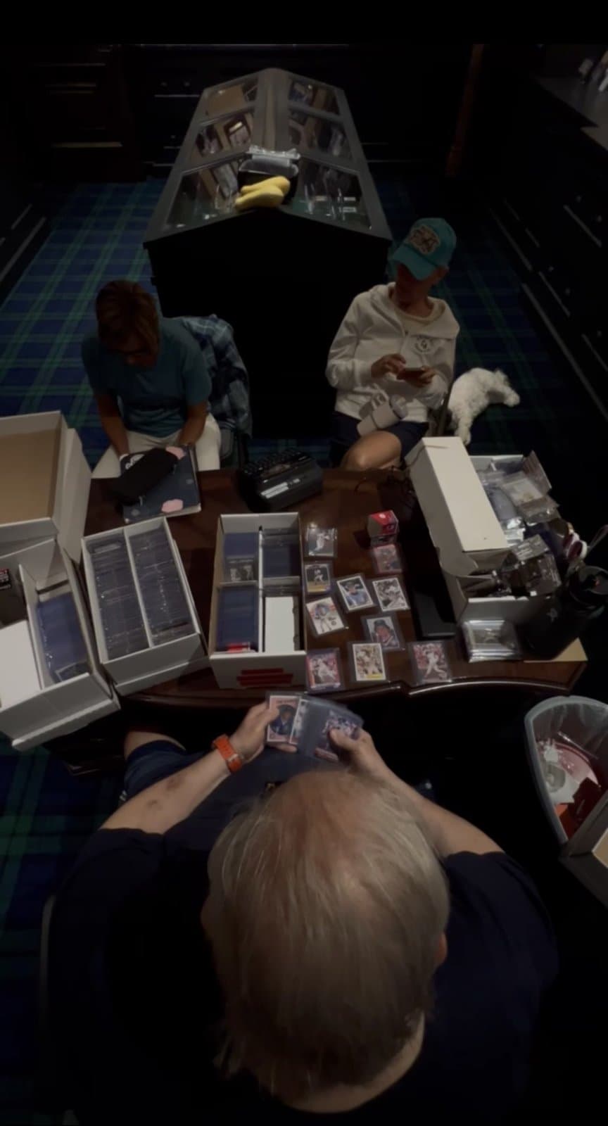 Overhead view of the sorting table, three people building packs from boxes of cards.