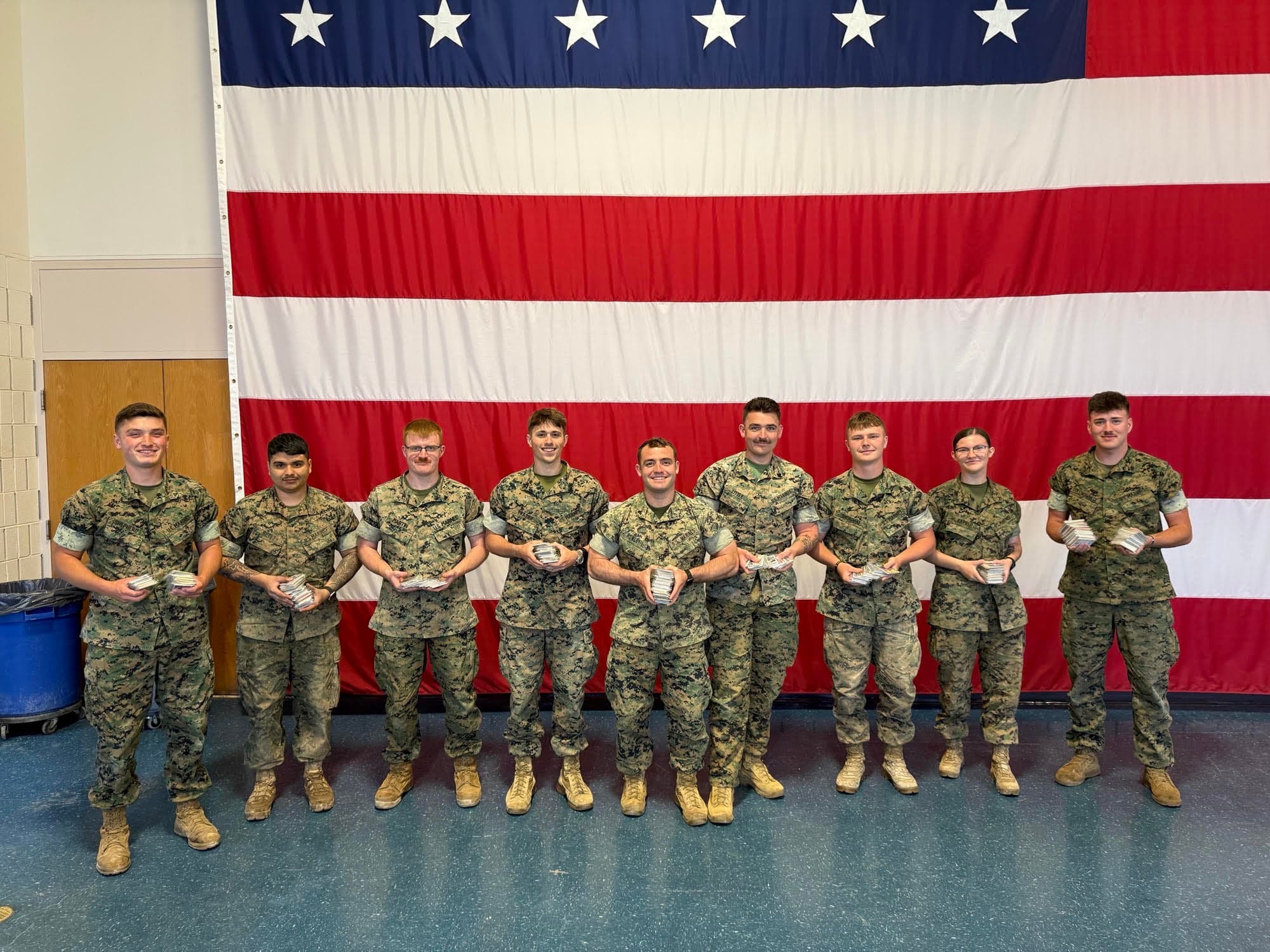 Service members holding packs of sports cards.